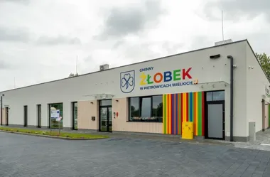 Budynek gminnego żłobka w Pietrowicach Wielkich z kolorowym logo i pasiastą elewacją przy wejściu.
